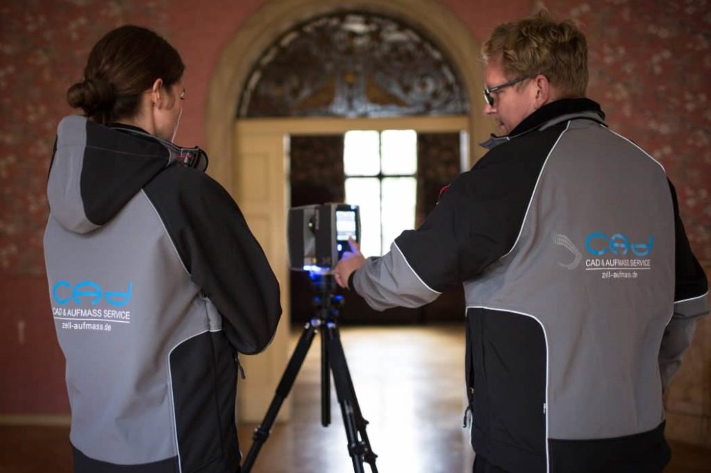 Zwei Vermesser bereiten den Laserscanner in einem Saal der Villen vor