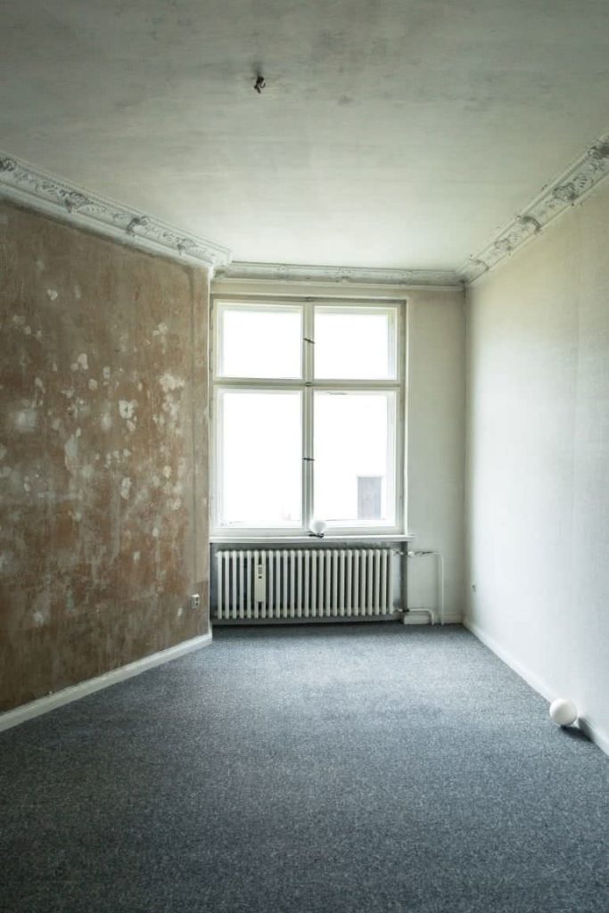 Leerer Raum mit hohem Fenster und Heizkörper